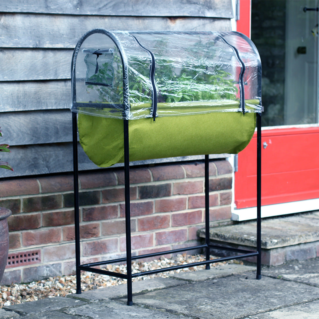 Vigoroot fabric table planter with many different types of plants inside it next to a wooden wall covered with a plastic cover